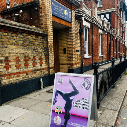 Outdoor sign for dance, acro, and gym classes in front of a brick building.