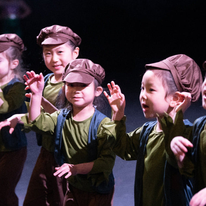 Children in matching costumes and hats performing on stage from our Musical Theatre & Performing Arts classes