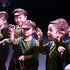 Children in matching costumes and hats performing on stage from our Musical Theatre & Performing Arts classes